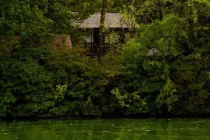 a house is surrounded by trees and green water